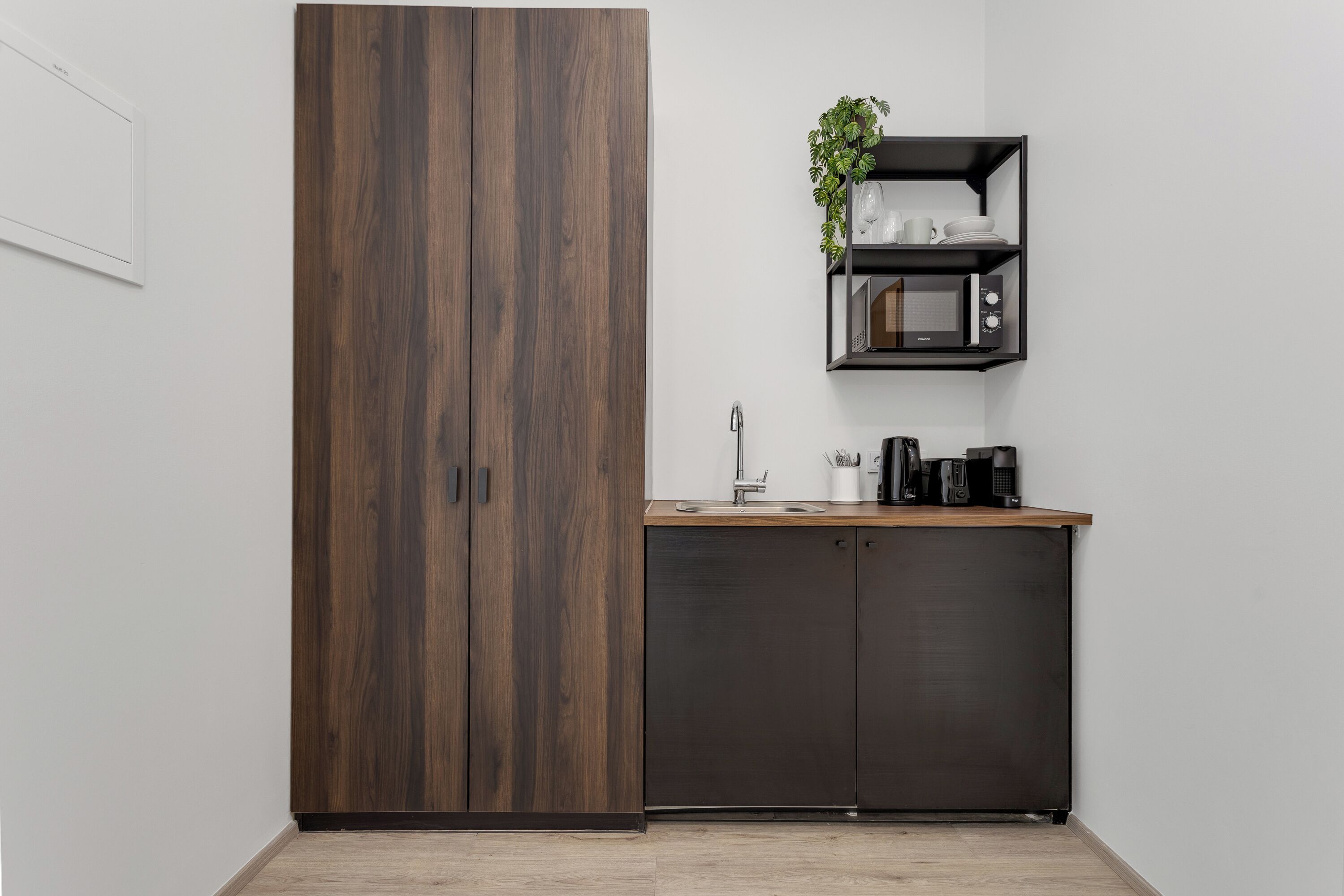 A kitchenette with a wooden cabinet, a microwave shelf, and a coffee maker.