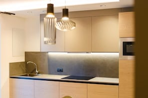 A modern kitchen with a built-in sink, stainless steel appliances, and pendant lighting. - Residence Diamant (Andalo)
