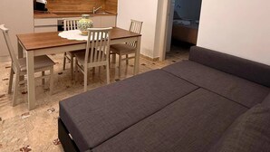 A compact living space with a dining area, kitchenette, and a sofa.