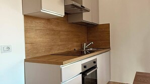 A compact kitchen with a built-in oven, a sink, and a wooden countertop.