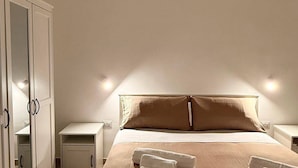 A bedroom with a bed, a nightstand, a wardrobe, and a mirror.
