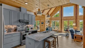 Une cuisine spacieuse dotée de plans de travail en granit, d’un îlot central et d’une grande fenêtre donnant sur un espace verdoyant.