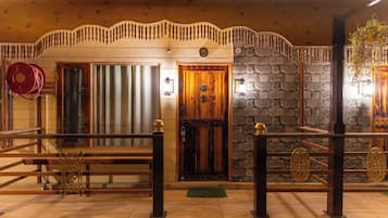 A wooden interior with a stone wall, a wooden door, and a metal gate.