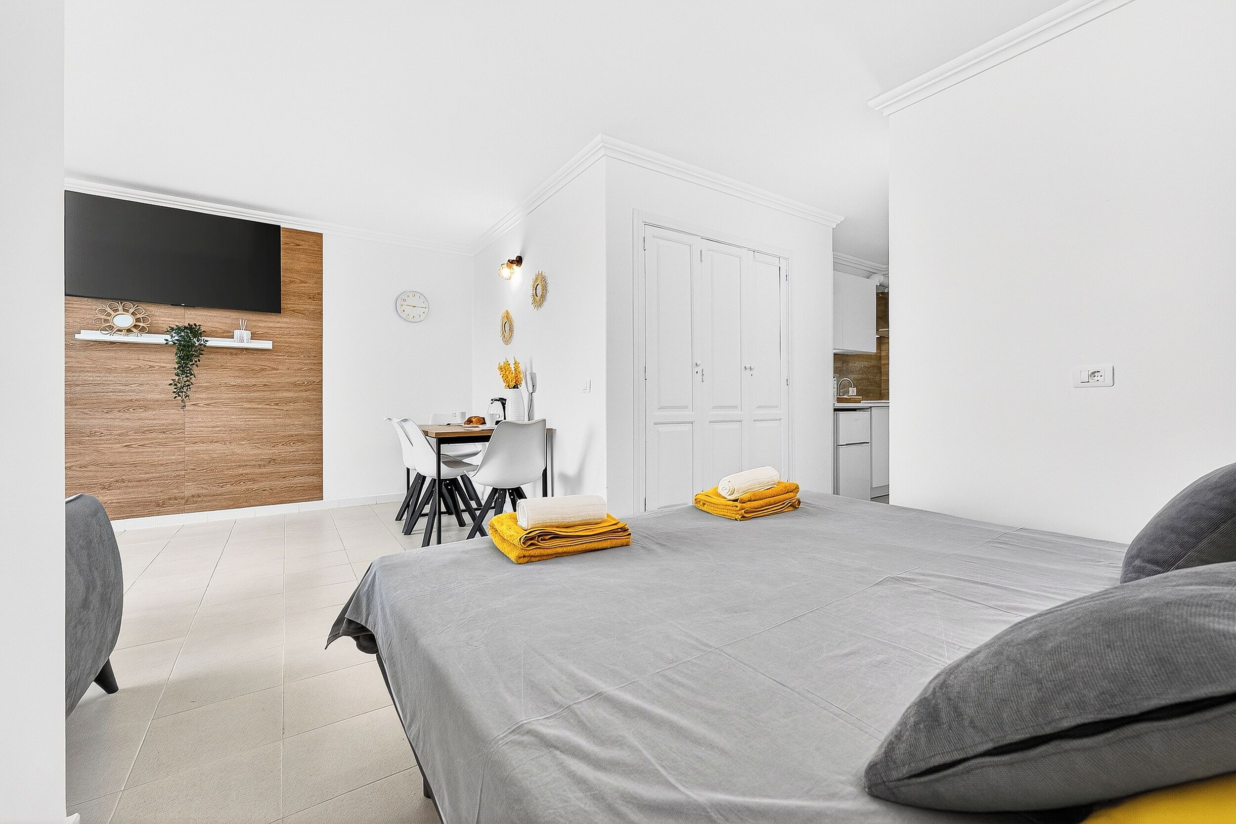 A modern hotel room with a bed, a desk, a chair, a TV, and a wardrobe.