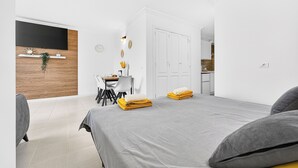 Ett modernt hotellrum med en säng, ett skrivbord, en stol, en TV och en garderob.