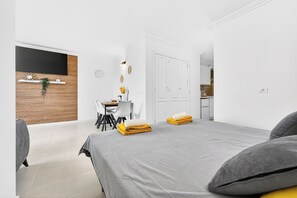 Ein modernes Hotelzimmer mit Bett, Schreibtisch, Stuhl, Fernseher und Kleiderschrank.