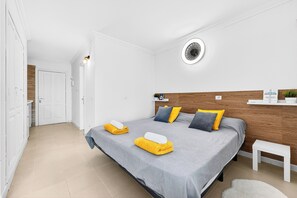 Ein Hotelzimmer mit Bett, Nachttisch, Wandleuchte und Tür.