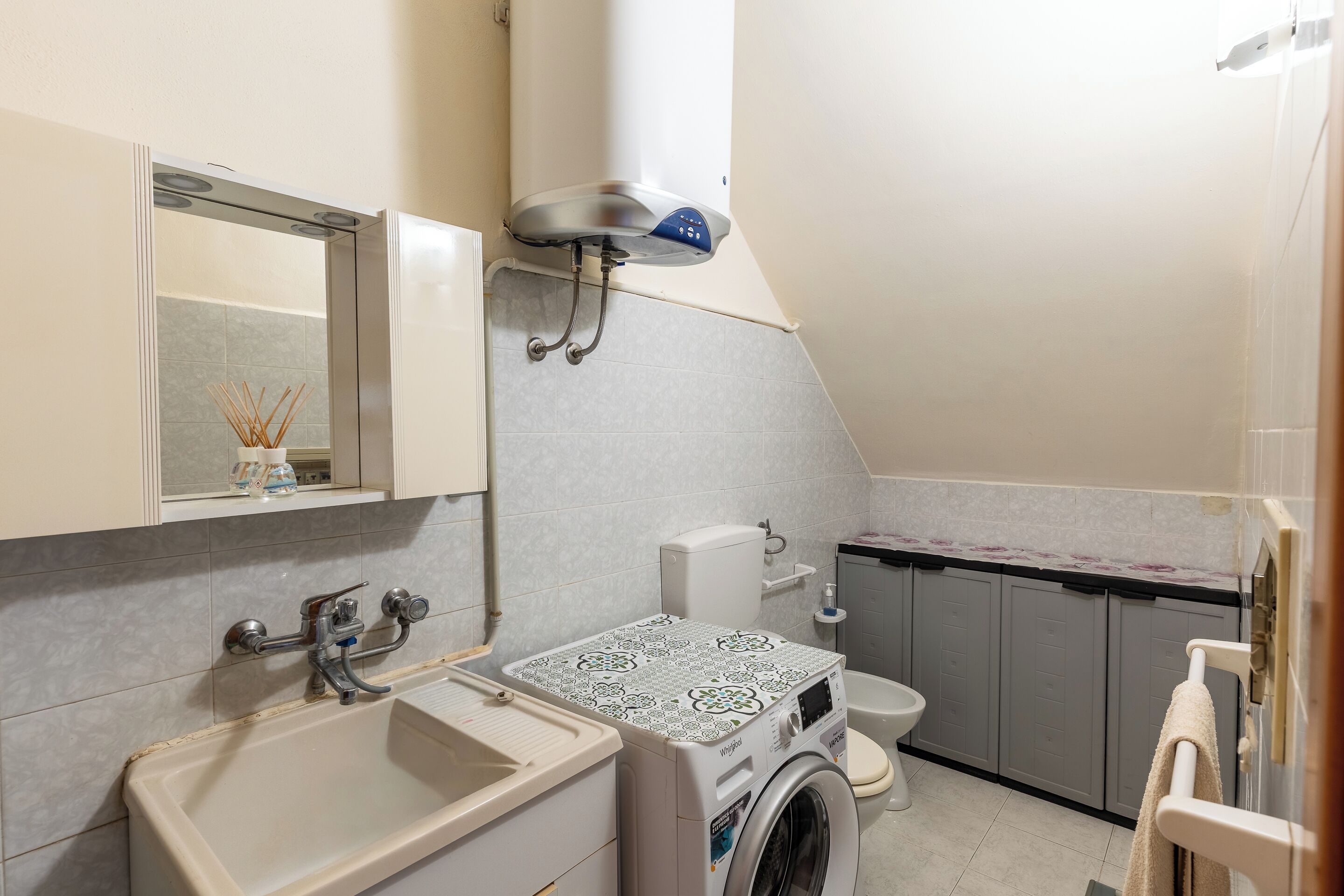 A compact bathroom with a sink, toilet, and washing machine.