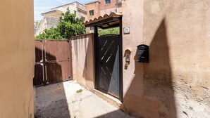 Un estrecho callejón con una entrada portonada, un buzón y el número 71.