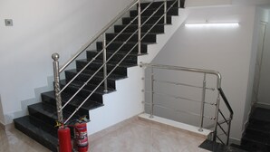 Una escala amb graons negres, una barana metàl·lica i dos extintors vermells.