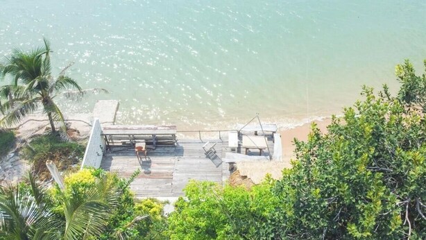 A wooden deck with lounge chairs overlooking a beach.