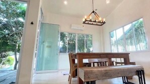 A spacious room with a large window, a wooden bench, and a hanging light fixture.