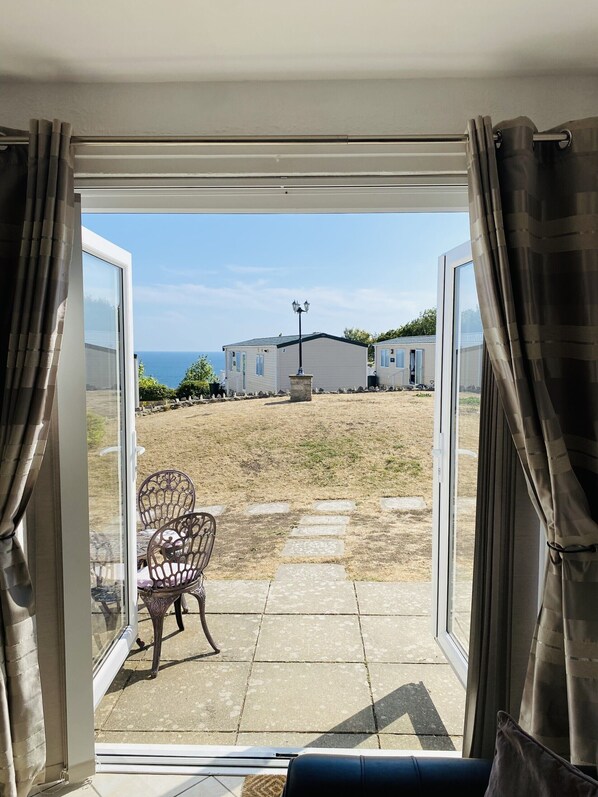 A view from a room with a sliding glass door to a patio area with a chair and a lamp post.