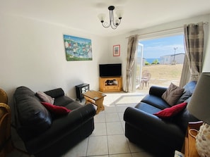A living room with two black sofas, a wooden coffee table, a television, and a painting on the wall.
