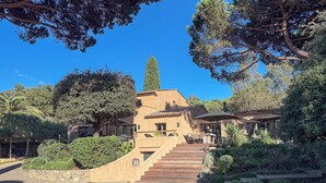 A Mediterranean-style villa with a terracotta facade, a wooden staircase, and a garden with various plants and trees. - Recently renovated villa with a fantastic garden not far from the beaches of Gigaro (La Croix-Valmer)