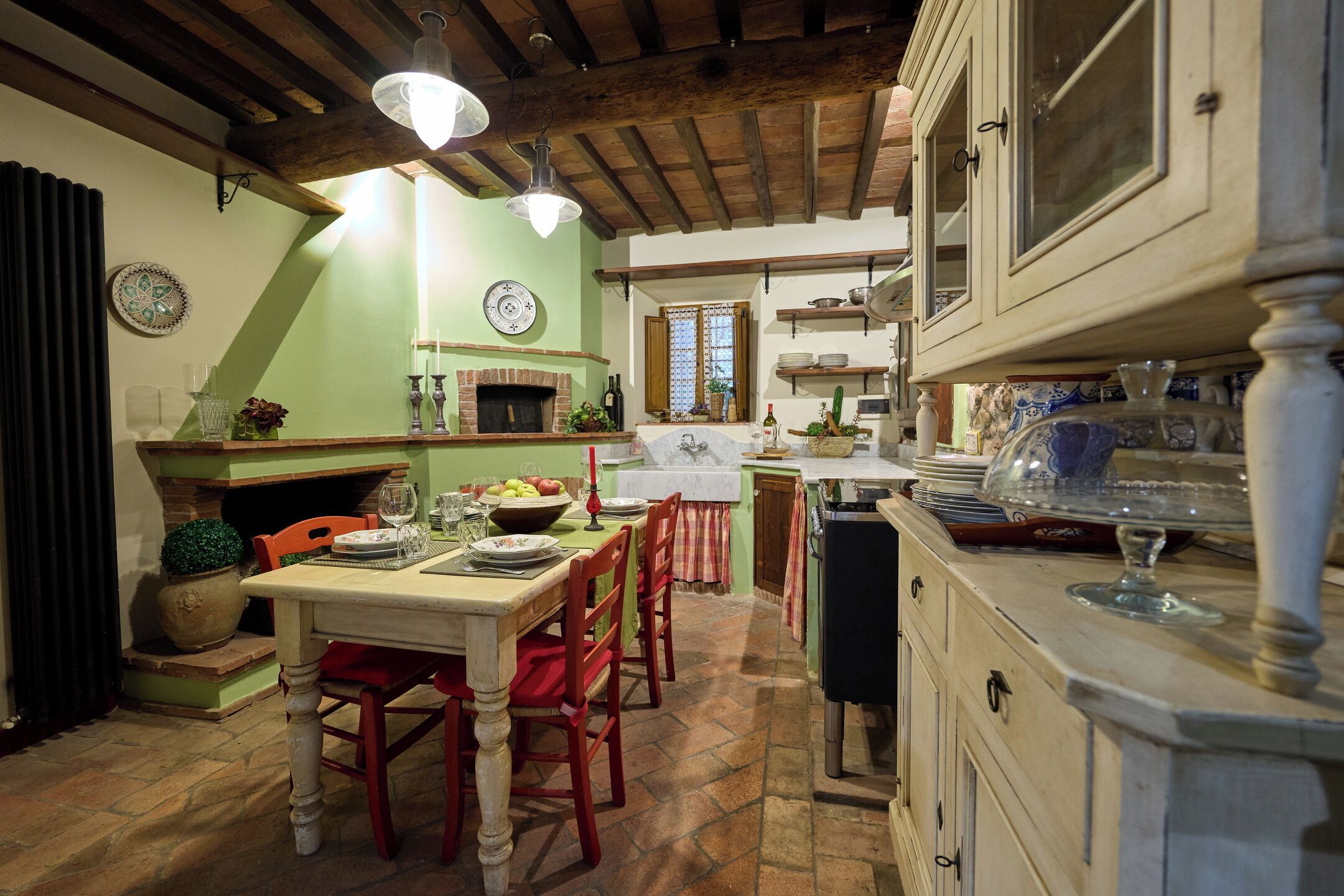 A rustic kitchen with a dining table, chairs, a fireplace, and a variety of kitchenware.