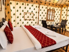 Habitación de hotel con cama, dos sillas, una mesa y ventana.