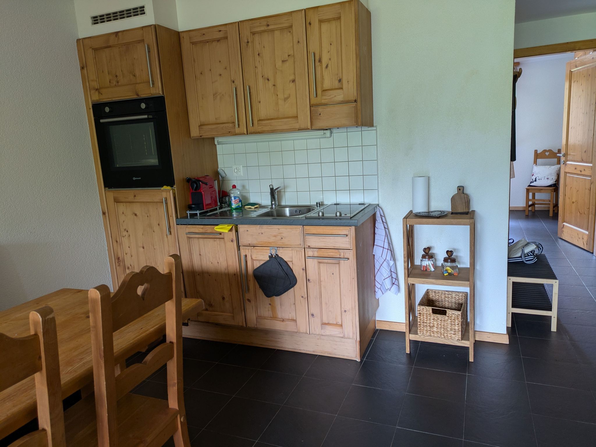 Une cuisine de taille réduite avec des meubles en bois, un four noir et un pare-feu en carreaux.