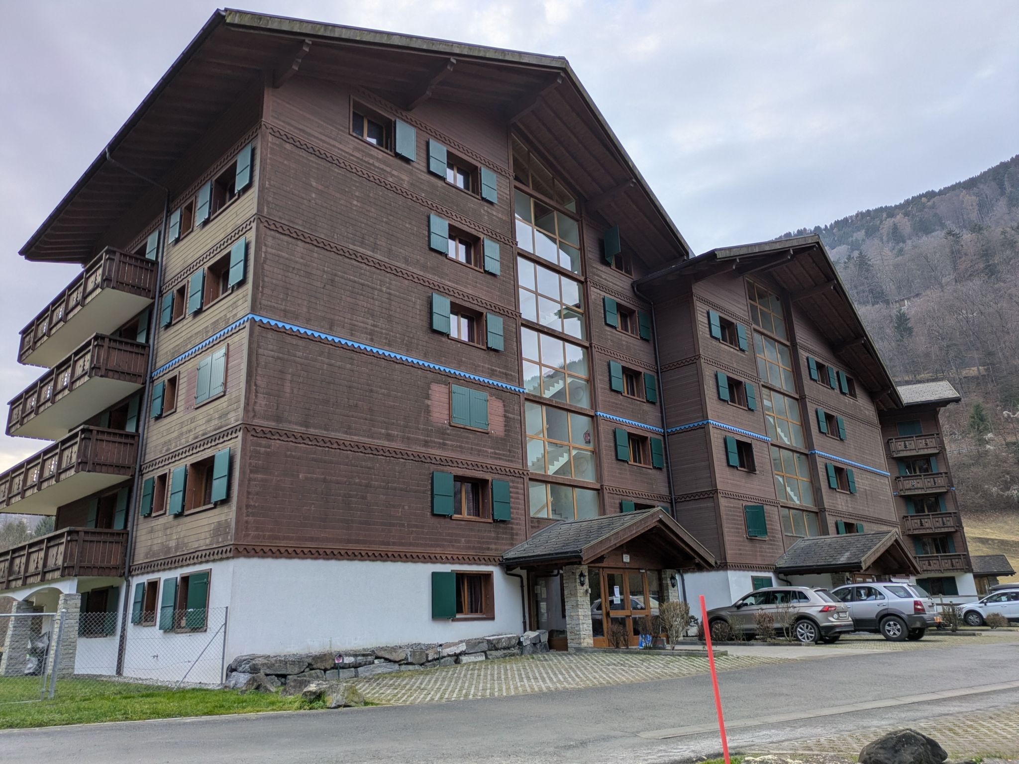 Un hôtel à plusieurs étages doté de balcons, d’une façade en pierre et d’un espace de stationnement.