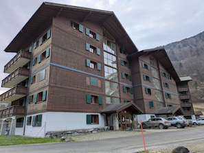 Ein mehrstöckiges Hotel mit Balkonen, einer Steinfassade und einem Parkplatz.