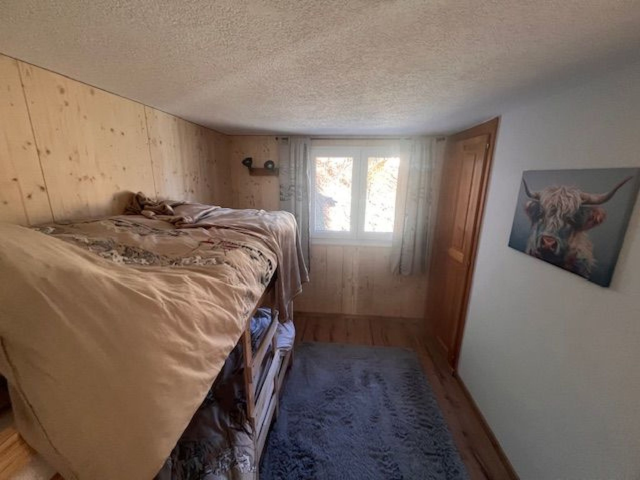 Une petite pièce confortable, avec un lit, une fenêtre et un tableau accroché au mur.