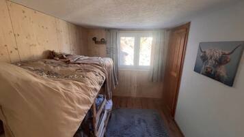 Une petite pièce confortable, avec un lit, une fenêtre et un tableau accroché au mur.