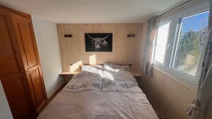 Une chambre à coucher avec un lit, des murs recouverts de panneaux en bois, une fenêtre et une porte.