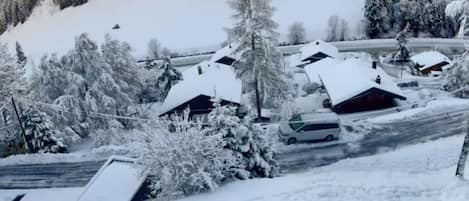 Un pueblo cubierto de nieve con casas, una carretera y una montaña al fondo.