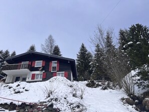 A two-story house with a balcony, surrounded by snow-covered ground and trees. - Chalet Violeta, (Morgins), by Interhome (Morgins)