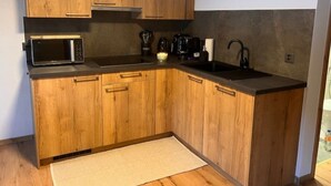 Une cuisine avec des meubles en bois, un four à micro-ondes, une machine à café et un évier.