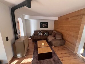 Ein kompakter Wohnraum mit einer braunen Couch, einem kleinen Couchtisch und einer Wand mit Holzverkleidung.