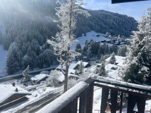 A snow-covered village with buildings and trees, a wooden fence, and a mountain in the background. - Chalet Violeta, (Morgins), by Interhome (Morgins)