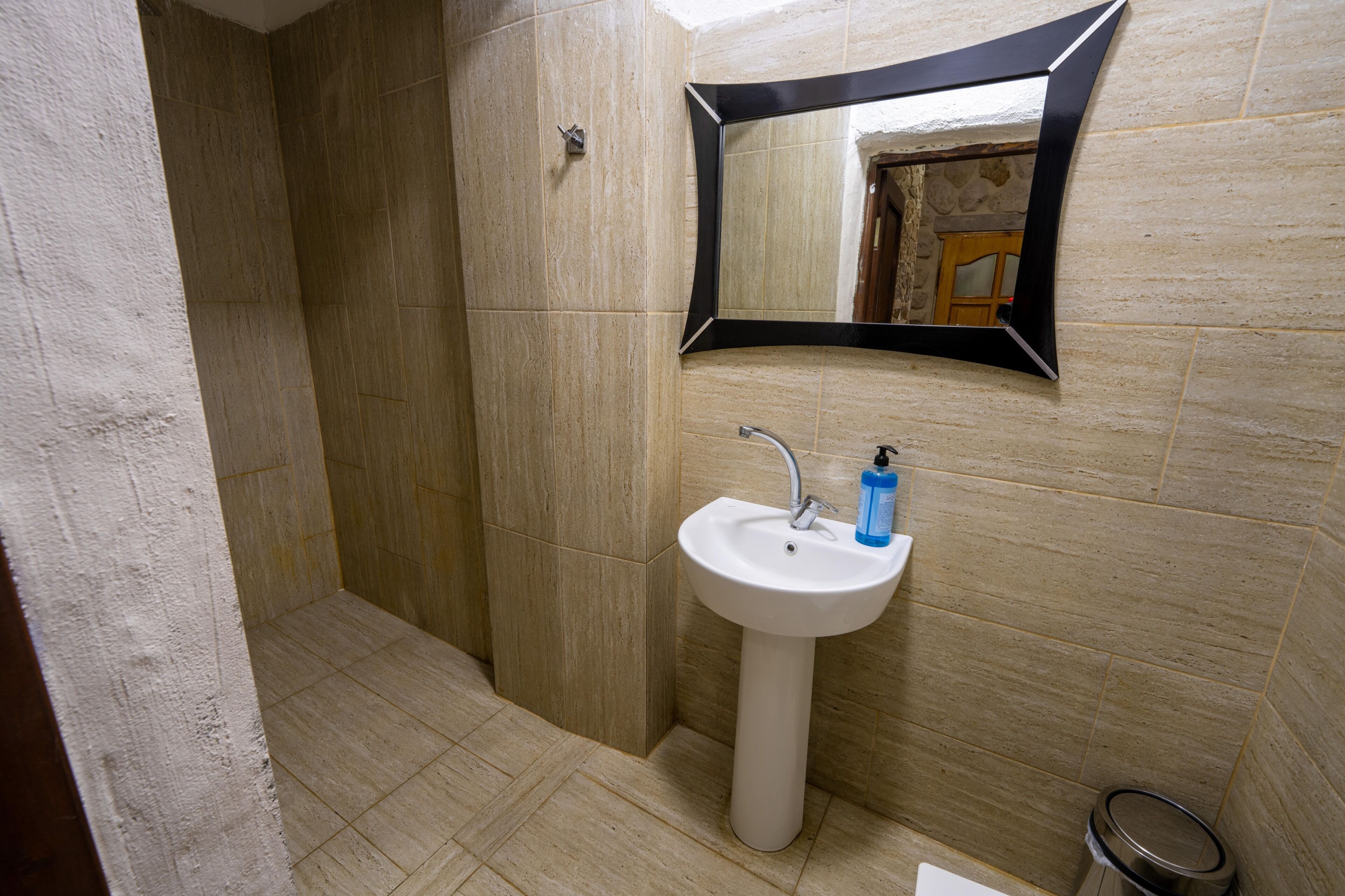 A bathroom with a sink, mirror, and shower.