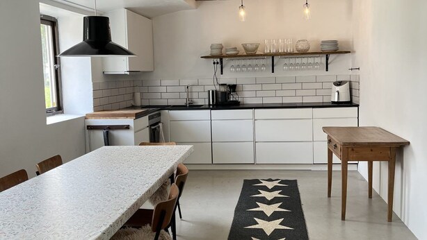 A modern kitchen with white cabinets, a black countertop, and a wooden ceiling beam.