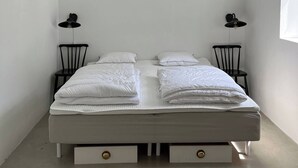 A bedroom with a bed, two chairs, a ceiling fan, and a window.