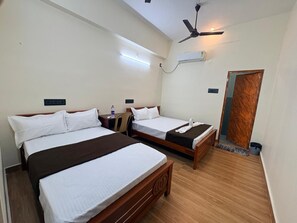 Habitación de hotel con dos camas, un ventilador de techo, un equipo de aire acondicionado y una puerta de madera.