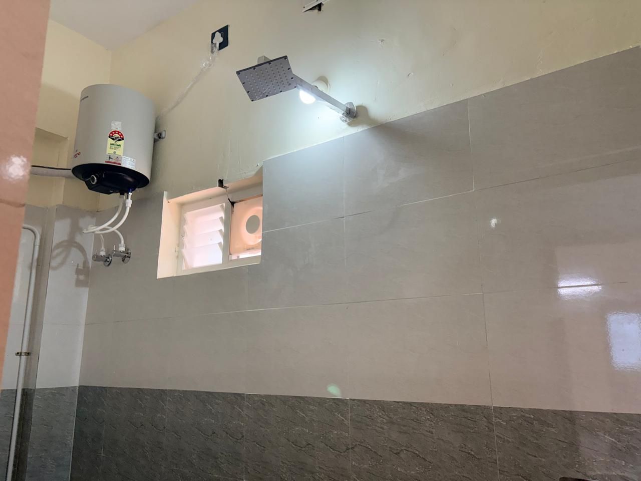 Un baño con ducha, calentador de agua y un ventanal.