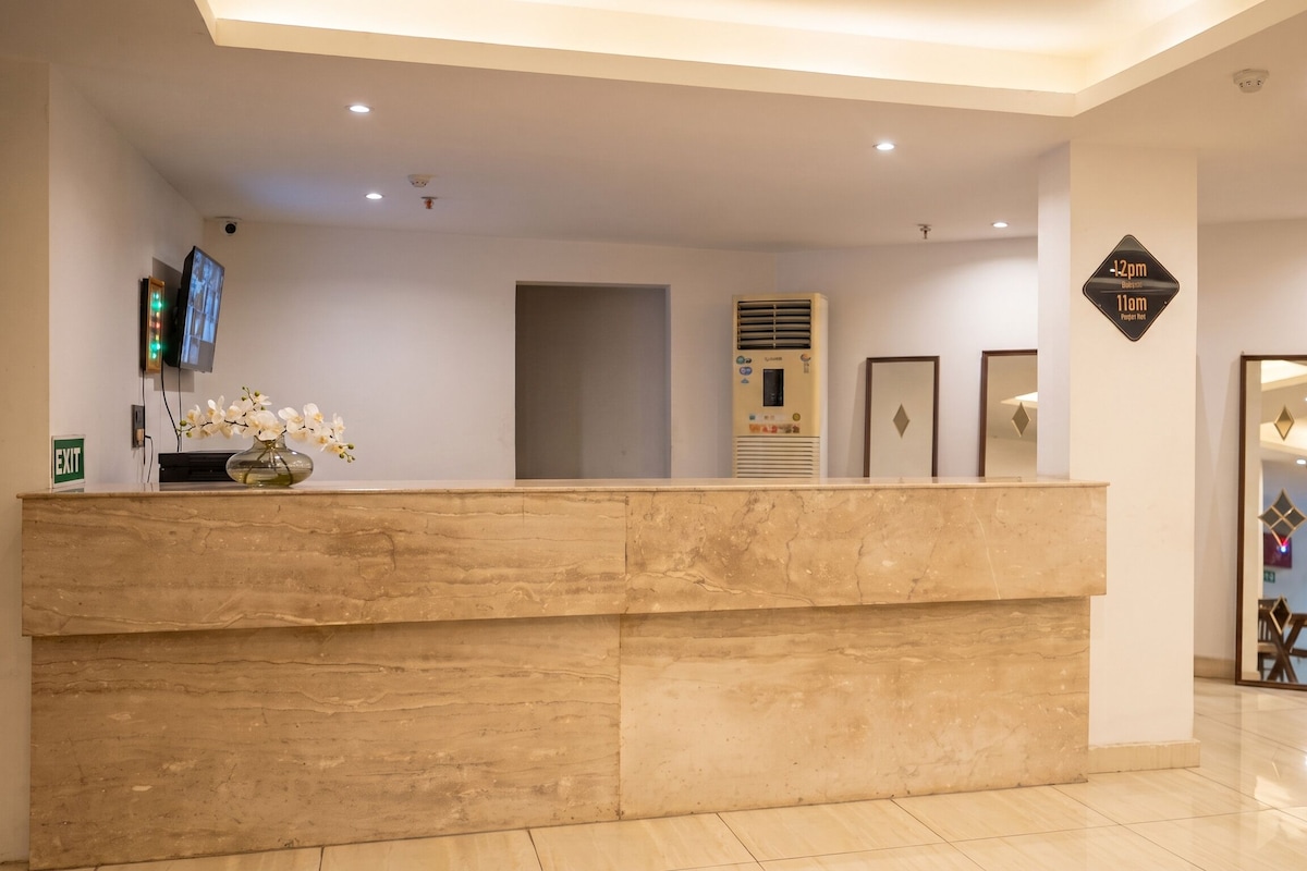 A reception desk with a flat-screen TV, a vase with flowers, and a wall-mounted air conditioning unit.