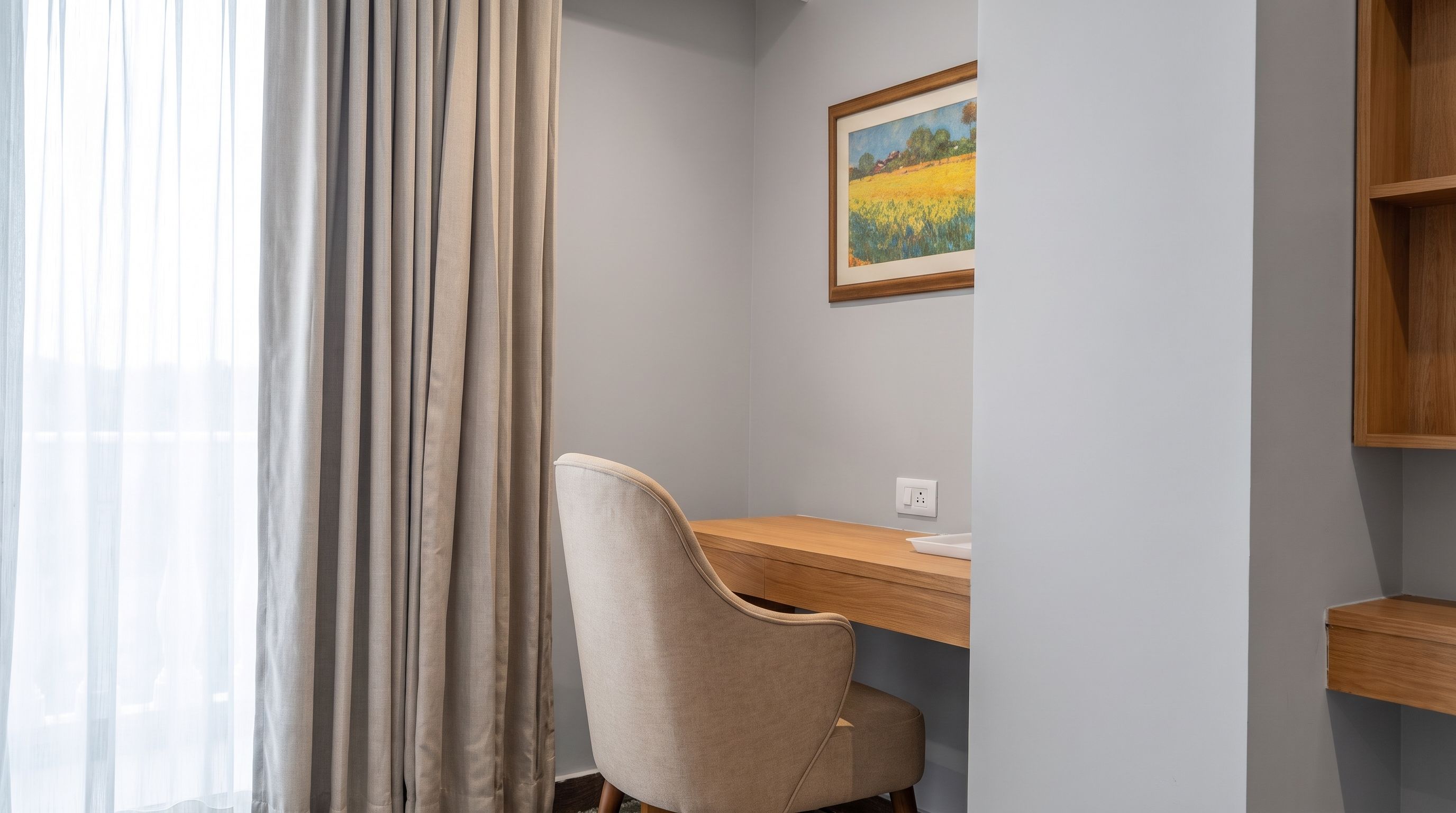 A room with a desk, chair, and a painting on the wall.