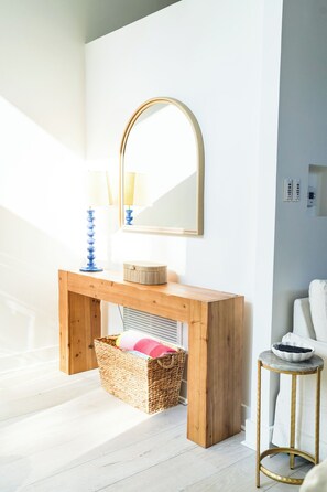 Ein Badezimmer mit einem Holzkosmetikschrank, einem Spiegel, einem Handtuchhalter und einem kleinen Hocker.