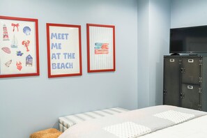 Ein Schlafzimmer mit einem Bett, einem Fernseher auf einem Schrank und drei gerahmten Bildern an der Wand.