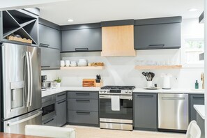 A modern kitchen with a stainless steel refrigerator, a built-in oven, and a dishwasher. - Fall Special! Newly updated large home with pool! (St Simons Island)