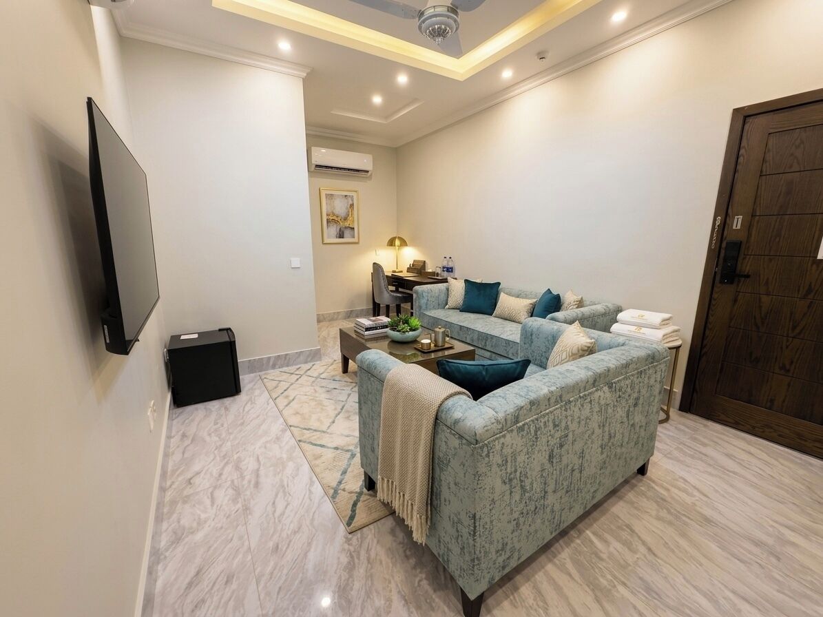 Una sala moderna con un conjunto de sofá, un televisor de pantalla plana, un escritorio con lámpara y una puerta.