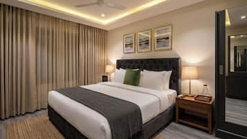 A hotel room with a large bed, a nightstand, a lamp, a ceiling fan, and a view of the outside through the window.
