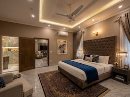 A modern bedroom with a large bed, a ceiling fan, a nightstand, and a view of a bathroom.