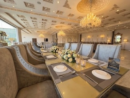Un comedor formal con una larga mesa, asientos acolchados, candelabros y detalles decorativos en el techo.