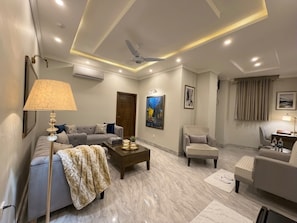Una sala de estar moderna con sofá, sillón, mesa de centro y ventilador de techo.