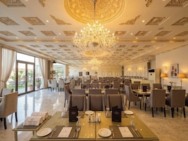 Un comedor amplio con múltiples mesas, elegantes candelabros y vistas al exterior.