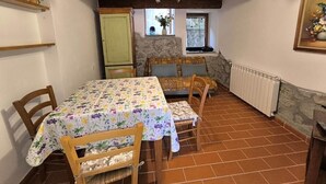 A rustic dining area with a table and chairs, a stone wall, and a window with a view. - Chalet in Maremma with Private Pool and Wi-Fi, Apt 23 (Castel del Piano)