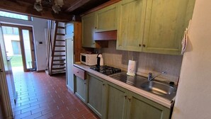 A kitchen with green cabinets, a stove, a sink, and a window. - Chalet in Maremma with Private Pool and Wi-Fi, Apt 23 (Castel del Piano)